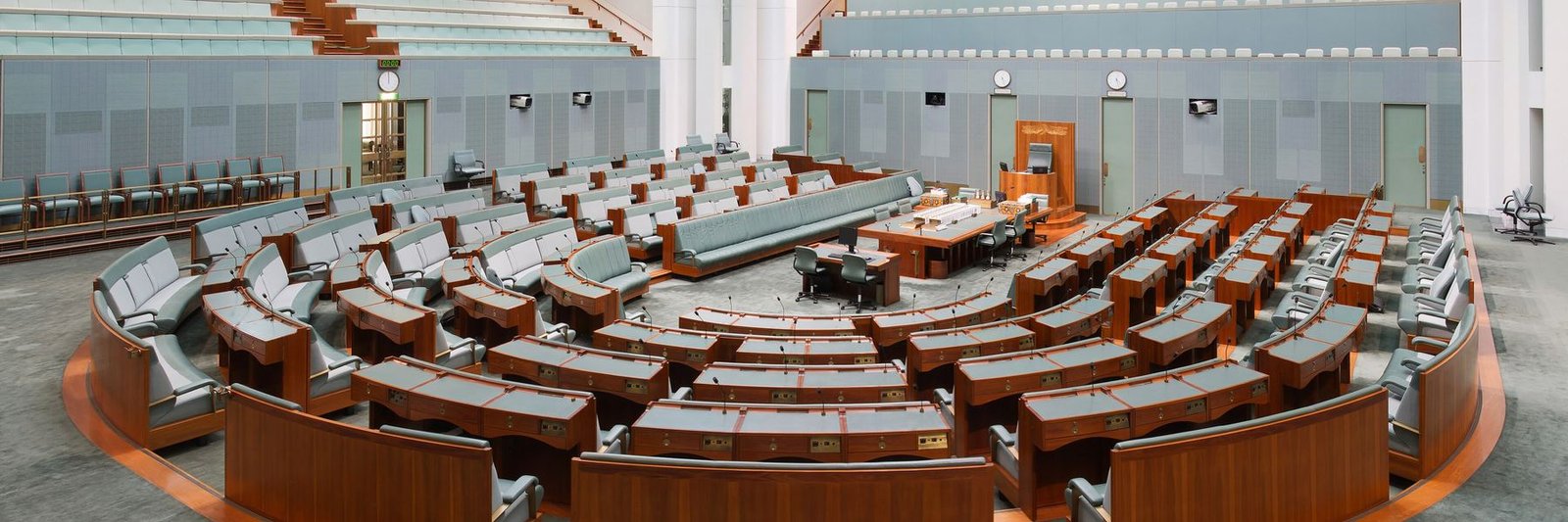 The empty chamber of the House of Representatives, with its curved rows of green leather seats