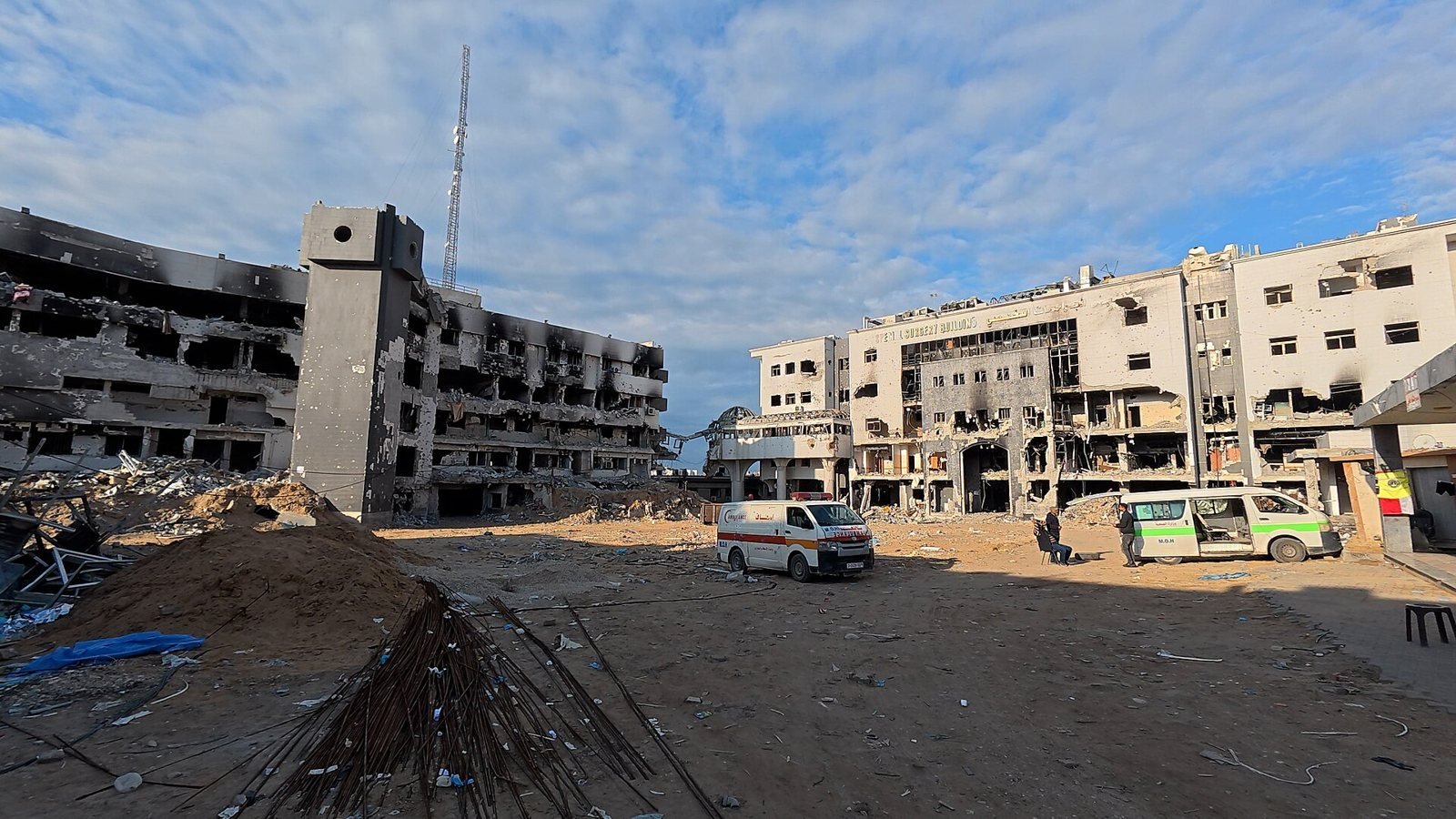 Aerial view of the burnt-out buildings and rubble of Al-Shifa Medical Complex with two ambulances in the forecourt